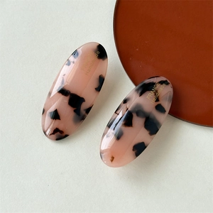 Macro detail of oval leopard print acetate hair clip with gold France Handmade logo