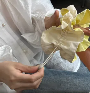 Detail of yellow and cream drawstring scrunchie with adjustable buckle and soft fabric texture