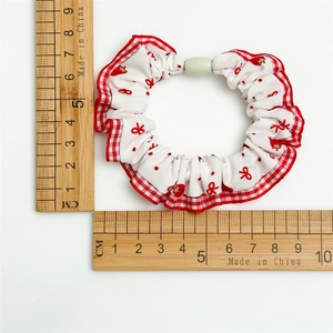 Detail of fabric scrunchie with red polka dot hearts and plaid lace ruffle edges