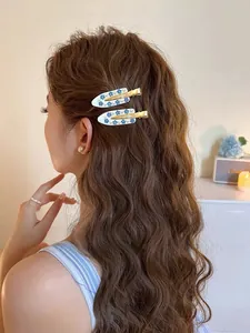 Detailed view of hair clips with blue flower motifs and pearls worn by a model