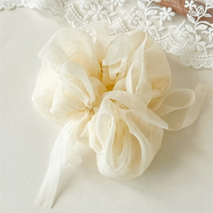 Detail of cream organza hair scrunchie with long ribbons and delicate lace background