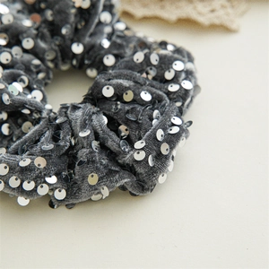 Detailed view of grey velvet scrunchie with sparkling silver sequins and soft texture