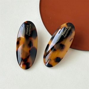 Macro view of handmade tortoiseshell acetate oval hair clips with gold foil lettering
