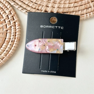 Detail of pink marble cellulose hair clip with colorful rhinestones on silver duckbill clip
