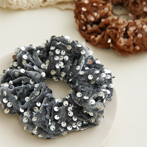 Macro shot of gray and brown sequin velvet scrunchies with metallic glitter detail