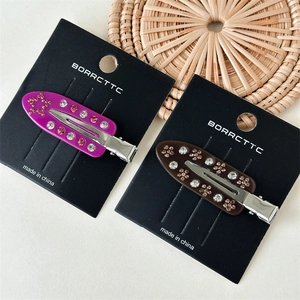 Detailed macro view of purple and brown acetate hair clips with inlaid colorful rhinestones