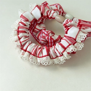 Detail of red and white checkered scrunchie with lace edges and oval decorative beads