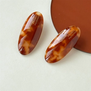Detailed close-up of amber tortoiseshell oval hair clips with France Handmade gold lettering