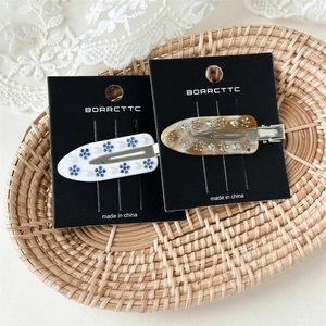 Detailed macro view of acetate floral duckbill hair clips with pearls and rhinestones