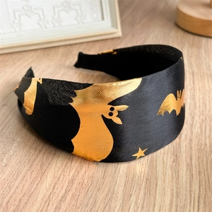 Close-up of wide Halloween headband with golden foil bat and star patterns on black satin