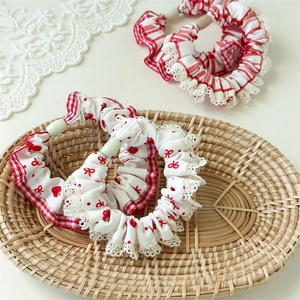 Detail of red gingham hair scrunchies with white lace trim and green beads in a basket