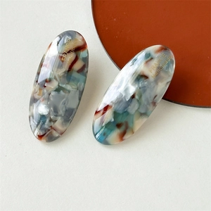 Detailed macro view of handmade acetate oval hair clip with marble texture and gold lettering