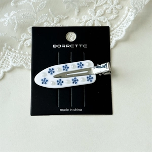Detailed macro view of white acetate hair clip with blue flowers and pearls on lace fabric