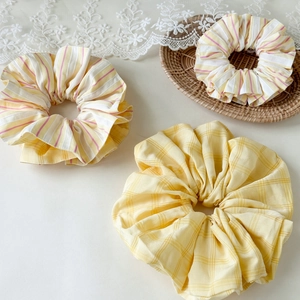 Detail of yellow striped and plaid fabric scrunchies on a lace decorative background