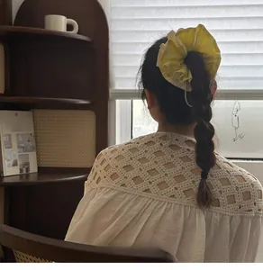 Detail of yellow large scrunchie with wavy edges styled in a bun hair look
