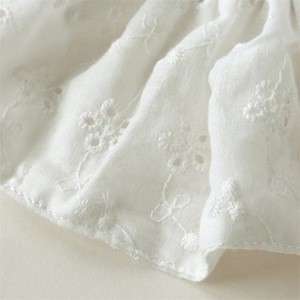 Close-up of white floral Broderie Anglaise embroidery lace fabric with delicate cutouts