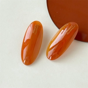 Detail of amber acetate oval hair clip showing polished texture and gold handmade logo