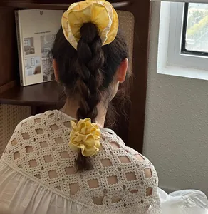 Detail view of yellow plaid scrunchies paired with a vintage crochet top on braided hair