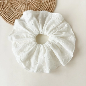 Close-up of white floral lace embroidery on oversized cotton scrunchie hair accessory