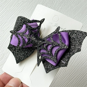 Detail of Halloween hair clip with purple ribbon bow and black glitter bat wing on card