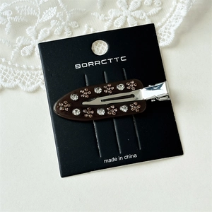 Detail of a brown acetate hair clip with crystal flower patterns on a lace background