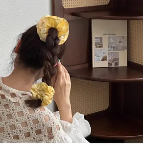 Close-up of set of 2 yellow checkered oversized scrunchies in a stylish ponytail