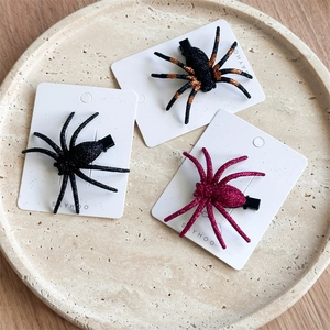Detailed view of glitter spider hair clips in black, orange, and magenta on stone plate
