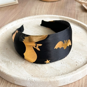 Close-up of black fabric Halloween headband featuring golden bats and star patterns
