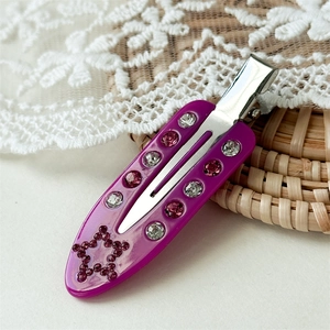 Macro shot of purple acetate hair clip with sparkling rhinestones and star pattern