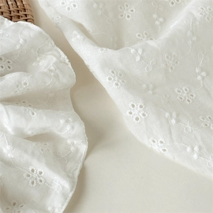 Detailed macro view of white floral lace embroidery on breathable cotton fabric