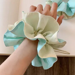 Macro detail of oversized dual-tone mint green and beige pleated scrunchie hair accessory