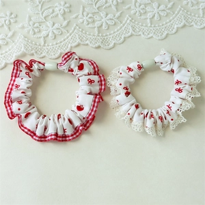 Detailed close-up of red polka dot hair scrunchies with plaid and lace trim edges