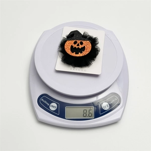 Détail d'une pince à cheveux citrouille d'Halloween pesant 8,6g sur une balance