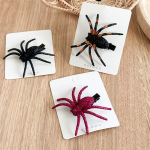 Detailed view of three glitter spider hair clips in black, orange, and pink on display card