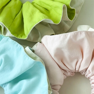 Macro detail of ruffled oversized hair scrunchies in pastel green, pink, and blue fabrics