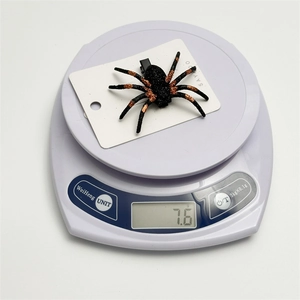 Glittery Halloween spider hair clip for girls shown on an electronic scale weighing 7.6g