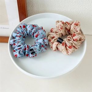 Gros plan de chouchous en tissu floral bleu ciel et beige sur une assiette en céramique