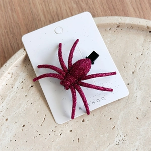 Detail of a sparkling red spider hair clip with glitter on a marble tray for Halloween