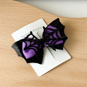 Detail of Halloween bat hair clip with purple ribbon and black spider web mesh design