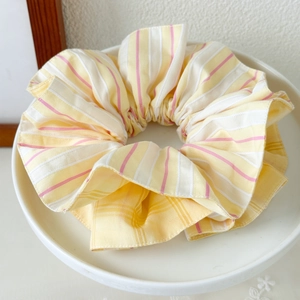 Detailed view of textured striped fabric on a large scrunchie in yellow, pink and white