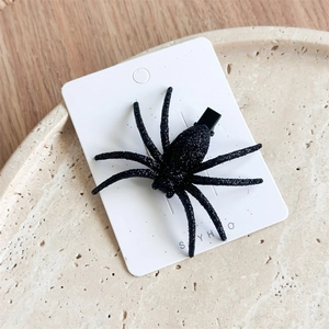 Close-up of black glittery spider hair clip for Halloween on white display card