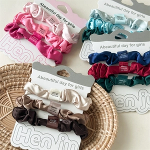 Bunte Satin-Haargummis im 3er-Set in einem Korb für elegantes Haarstyling präsentiert