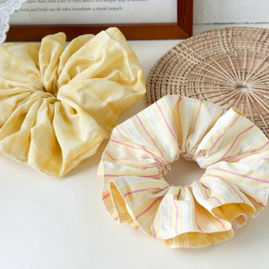 Detailed view of yellow plaid and striped fabric scrunchies on a wooden frame
