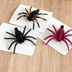 Three glittering Halloween spider hair clips in black, orange, and pink on card