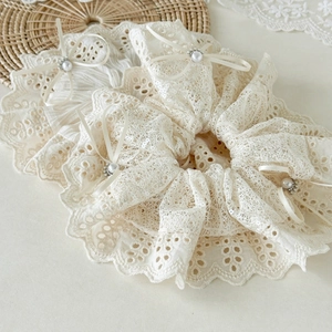 Detailed close-up of white lace hair scrunchies with delicate bows and small pearls