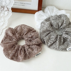 Detailed macro of French lace scrunchies in gold, silver, and white mesh fabric textures