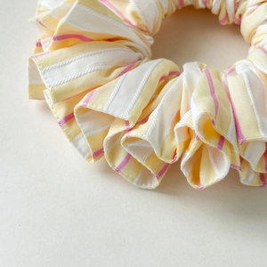 Close-up of yellow and pink striped fabric scrunchie with soft pleated texture