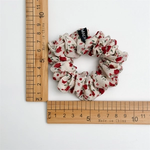 Chouchou en tissu fleuri avec fleurs rouges sur mousseline crème et échelle de mesure