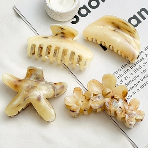 Detailed close-up of amber marble textured hair clips on a minimalist lifestyle background