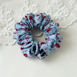 Gros plan d'un chouchou bleu clair à fleurs avec texture de tissu et fond en dentelle
